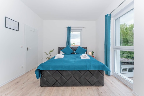A bedroom with a bed, a window, and a door.