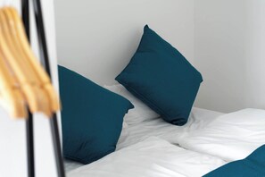 A bed with white bedding and teal pillows.