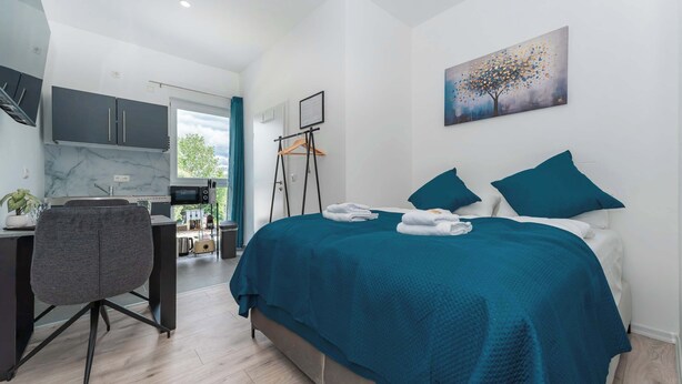 Un dormitorio moderno con cama, escritorio y silla.