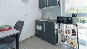 Cocina compacta con microondas integrado, refrigerador pequeño y ventana con vistas al exterior.