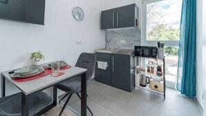 Una cocina moderna con armarios grises, horno empotrado y ventana con vistas a zonas verdes.