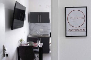 A framed sign on a wall indicating 'Lit Living Apartment 6' with a modern kitchen in the background.