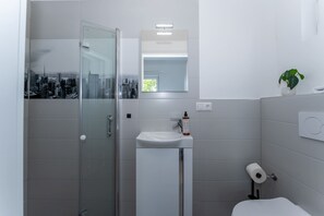 A modern bathroom with a glass shower enclosure, a white sink, and a toilet. - LiT LiVING: Luxus | Box SprIng | Kitchen | Parking (Altenstadt)