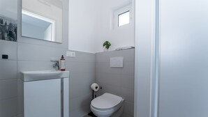 A bathroom with a toilet, sink, and a small window. - LiT LiVING: Luxus | Box SprIng | Kitchen | Parking (Altenstadt)