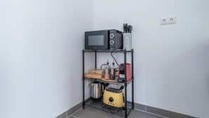 A kitchen area with a microwave, toaster, kettle, and a shelf with utensils. - LiT LiVING: Luxus | Box SprIng | Kitchen | Parking (Altenstadt)