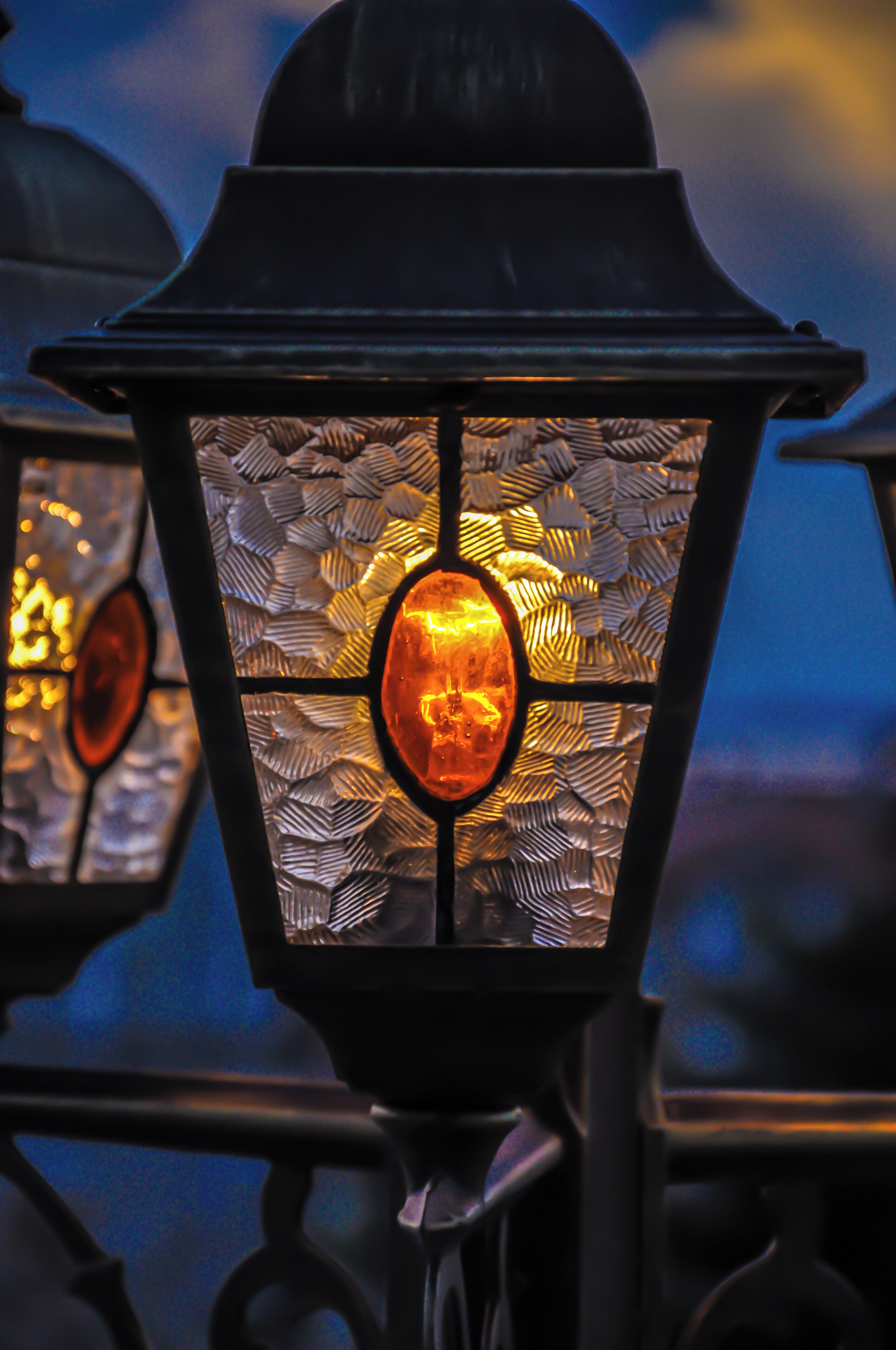 Primer plano de una farola decorativa con un diseño de vidrio estampado y un elemento central brillante.
