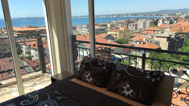 Un dormitorio con un ventanal grande que da a una vista panorámica de la ciudad y el mar.
