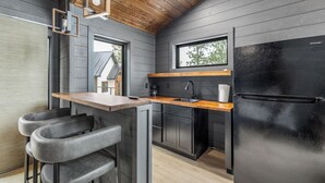 Eine moderne Küche mit Holzbalkendecke, schwarzen Schränken, einem schwarzen Kühlschrank und einer Holzarbeitsplatte.