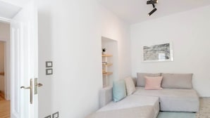 A modern, minimalist room with a sofa set, a small table, and a wall-mounted shelf with decorative items.