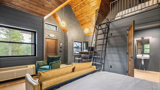 A modern loft bedroom with a loft bed, wooden ceiling, and a large window. - Modern Black Hills Cabin · Romantic Getaway · Hot Tub · Near Deadwood (Sturgis)