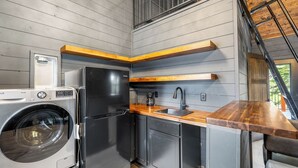 A compact kitchen with a washing machine, a refrigerator, and a wooden countertop. - Modern Black Hills Cabin · Romantic Getaway · Hot Tub · Near Deadwood (Sturgis)