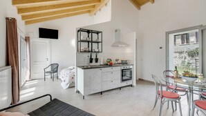 Une cuisine moderne dotée d’un îlot central, d’un coin repas avec des chaises en métal et d’une grande fenêtre offrant une vue dégagée.