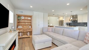 A modern living room with a fireplace, a sectional sofa, and a wooden bookshelf.
