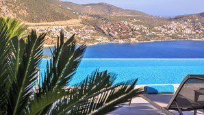 Vista da piscina com mar azul cristalino e uma cidade ao fundo.