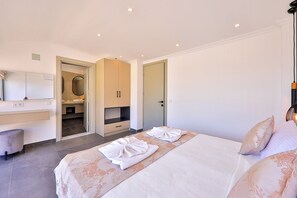 A hotel room with a bed, a desk, a mirror, and a bathroom visible through an open door.