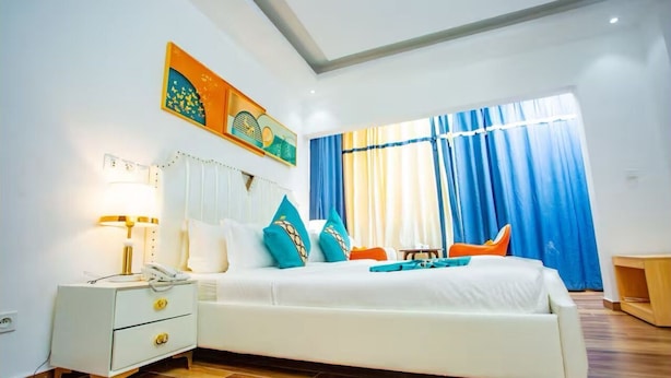 A modern bedroom with a large bed, bedside tables, a nightstand, and a window with curtains. - 520 HÔTEL et RESIDENCE (Abidjan)
