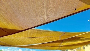 An outdoor pool area with wooden flooring, tables, and chairs, and a covered seating area with umbrellas. - 520 HÔTEL et RESIDENCE (Abidjan)