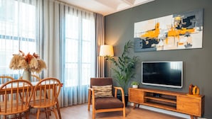 A living room with a wooden TV stand, a large flat-screen TV, a dining table with chairs, and a potted plant. - Galata Guest Teori (Istanbul)