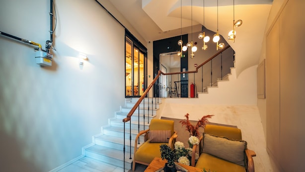 A modern living room with a staircase, a wooden coffee table with decorative items, and a sofa with cushions. - Galata Guest Teori (Istanbul)