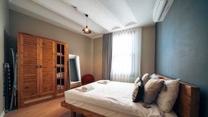A bedroom with a wooden bed, a wardrobe, and a chair. - Galata Guest Teori (Istanbul)