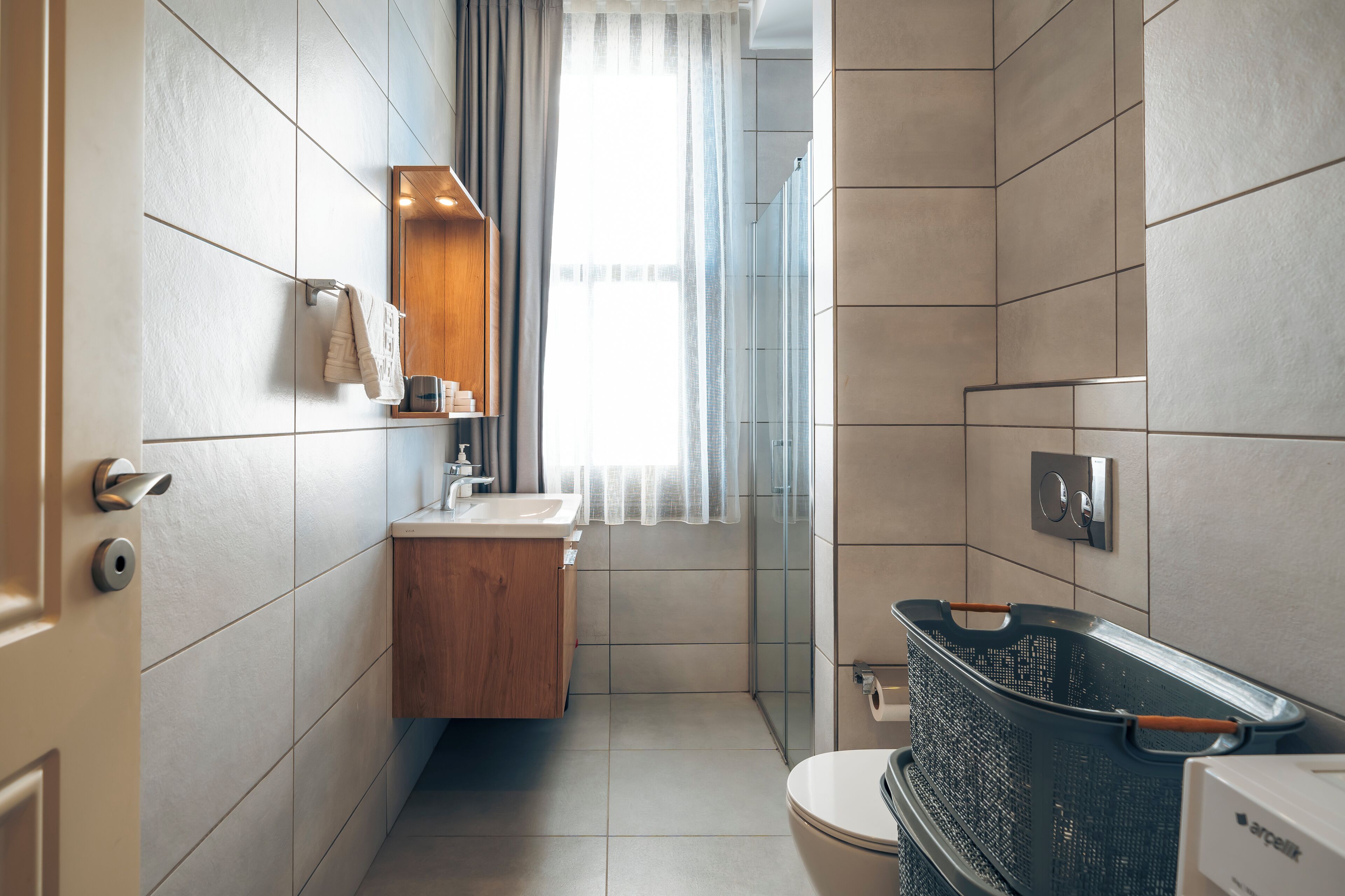 Ein modernes Badezimmer mit einem Holzwaschtisch, einer Duschkabine aus Glas und einer Toilette.