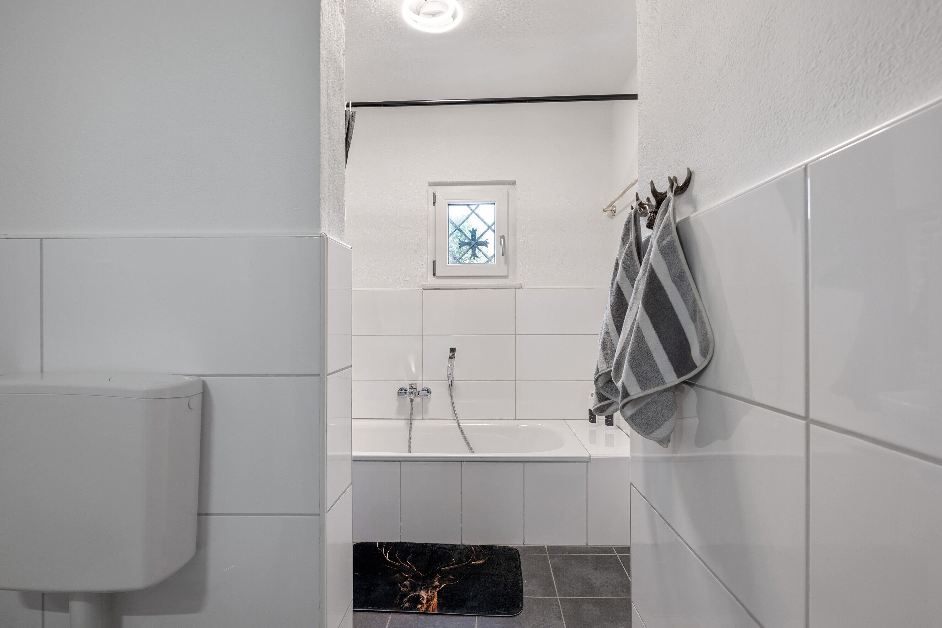 Une salle de bain équipée d’un WC, d’un lavabo, d’une fenêtre et d’un porte-serviettes.
