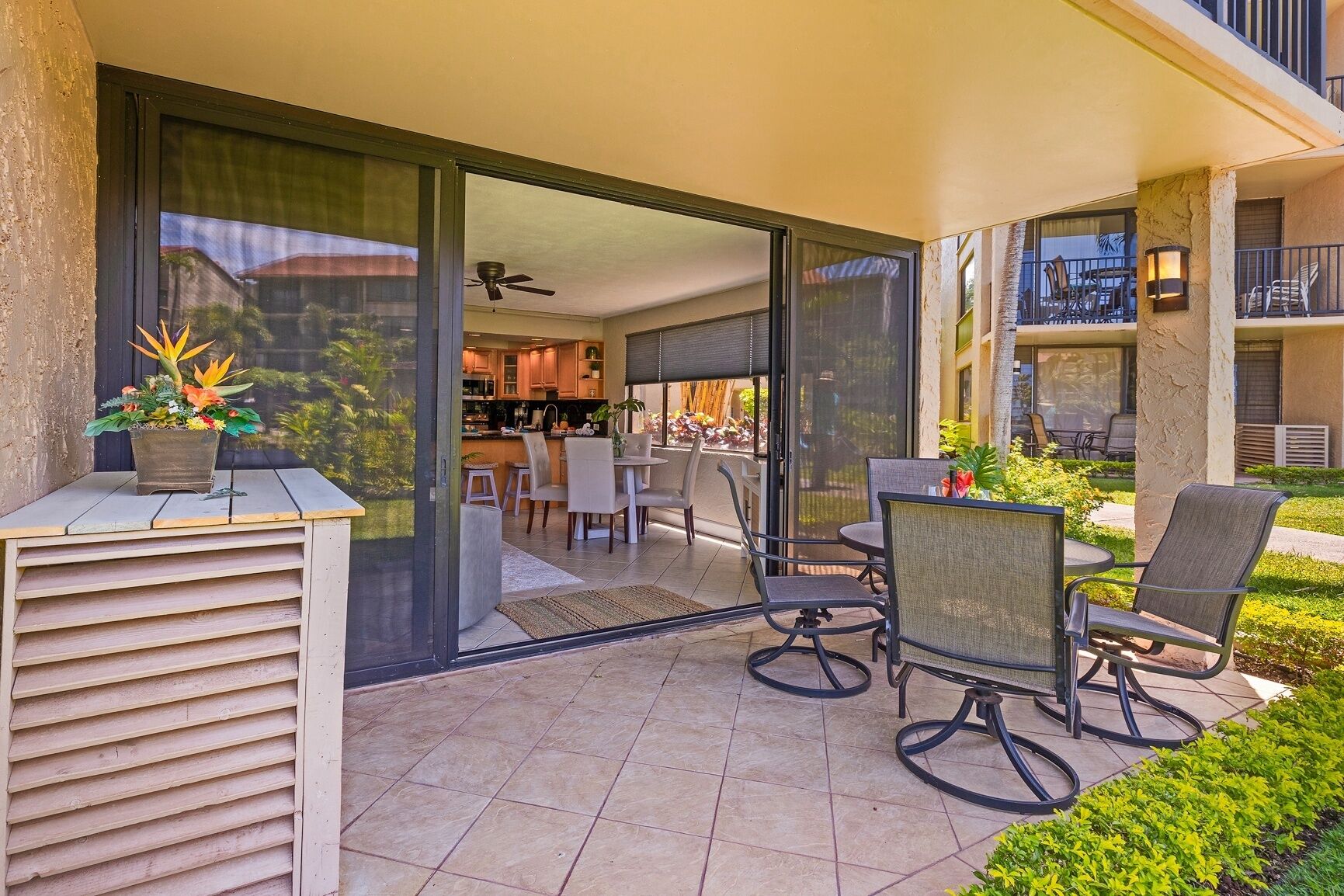 An outdoor patio with a dining area, including chairs and a table, and a view into the house.