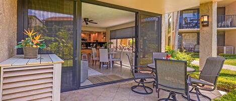 An outdoor patio with a dining area, including chairs and a table, and a view into the house.