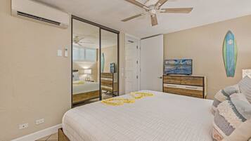 Un dormitorio con cama, ventilador de techo, cómoda, espejo y decoración con una tabla de surf.