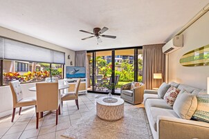 Una sala de estar moderna con televisor, zona de estar y vista a un jardín exuberante.