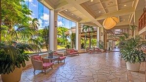 A spacious lobby with a tropical theme, featuring a stone floor, wicker furniture, and large windows offering views of the outdoors. - Kaanapali Shores 432 Studio Condo Condo (lahaina)