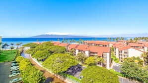 A resort with multiple buildings, a parking area, and a view of the ocean and mountains. - Kaanapali Shores 432 Studio Condo Condo (lahaina)