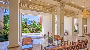 A spacious lobby with a glass coffee table, cushioned seating, and a view of a lush garden. - Kaanapali Shores 432 Studio Condo Condo (lahaina)
