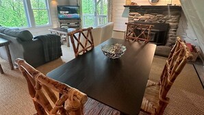 A cozy living room with a dark wooden table, woven chairs, a fireplace, and a television. - Killington A-frame 2 Bedroom Home (Killington)