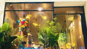 A modern interior with a wooden ceiling, hanging lanterns, and lush green plants. - Rosa May Hotel (Ho Chi Minh City)