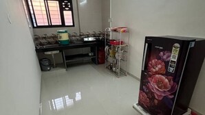 A kitchen with a refrigerator, sink, and various kitchen items. - 1BHK Comfy Stay 5 (Pune)