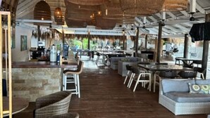 Ristorante open space con mobili in vimini, un'area bar e vista sull'esterno.