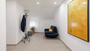 A spacious room with a large map on the wall, a black sofa with a yellow pillow, and a coat rack with a jacket. - Design Apartment in center(Piazza del Popolo)- Parking (Rome)