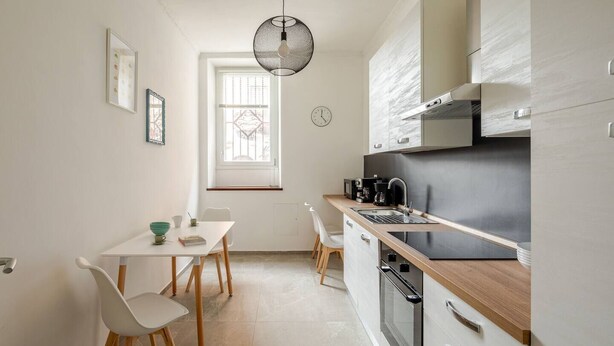 A modern kitchen with a wooden countertop, stainless steel appliances, and a window with decorative iron bars. - Design Apartment in center(Piazza del Popolo)- Parking (Rome)