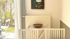 A dining area with a table, chairs, a wicker basket, a black vase, and a painting of a beach scene.