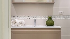 A bathroom with a white sink, a green vase, and a towel rack. - Scaramellino Accommodation (Vico Equense)