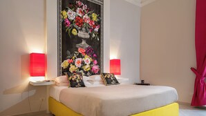A bedroom with a bed, two bedside lamps, a large floral painting, and a red curtain. - Scaramellino Accommodation (Vico Equense)