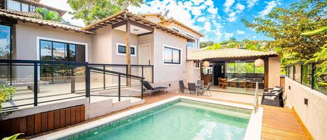 Una piscina al aire libre, sillones reclinables de piscina