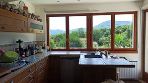 Eine Küche mit Holdekor, einem Geschirrspüler und einem großen Fenster mit Blick auf Berge und Grün.
