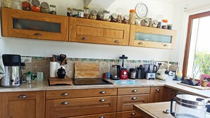 Eine Küche mit Holzausstattung, einer Arbeitsplatte und verschiedenen Geräten, sowie Gläsern auf der obersten Ablagefläche.