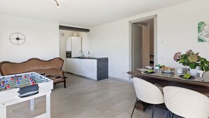 A modern living room with a foosball table, a sofa, a dining area with chairs, a kitchen island, and a pendant light. - Villa La Rocca (Taino)