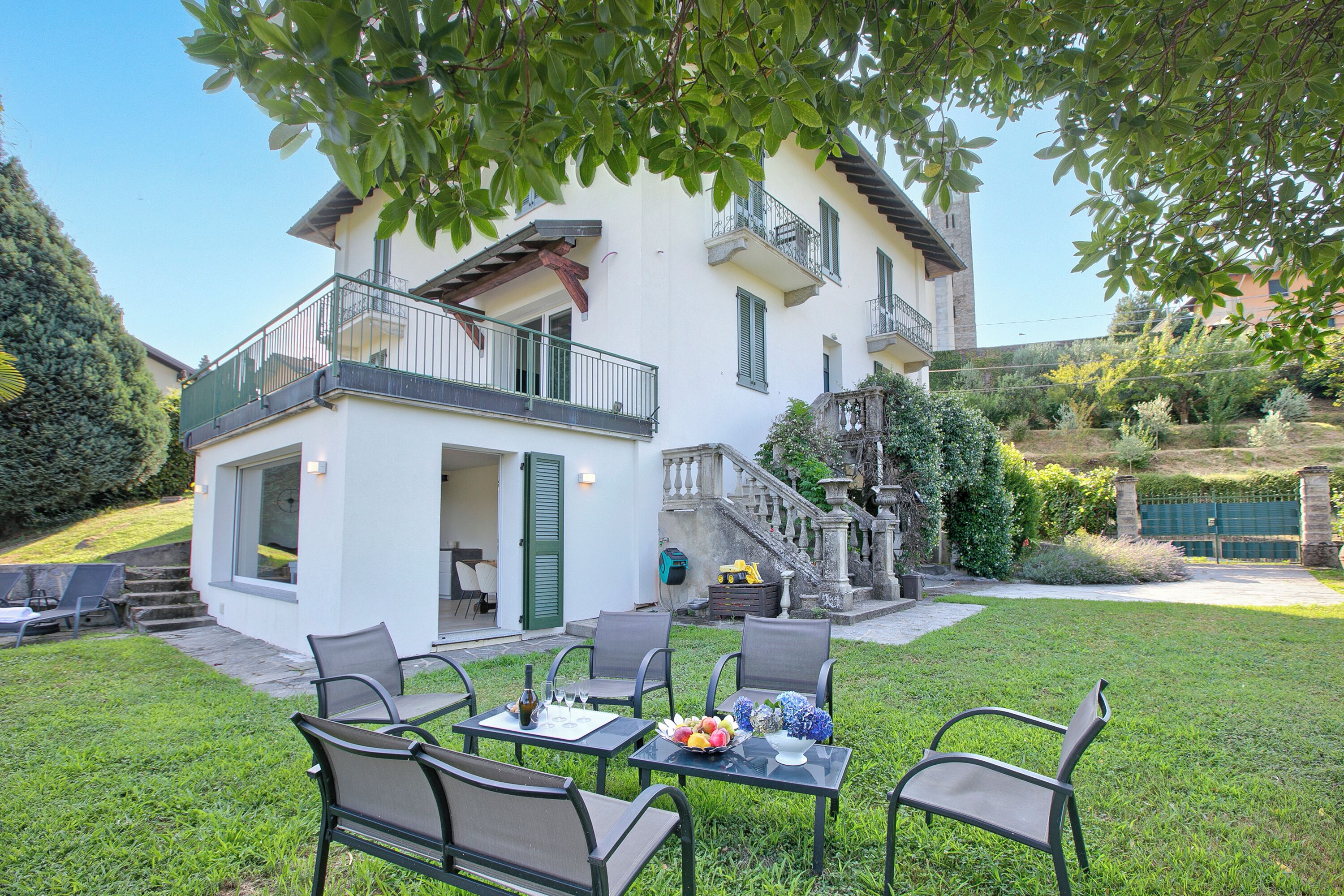 A two-story house with a balcony, outdoor seating area, and a staircase leading to the upper floor.