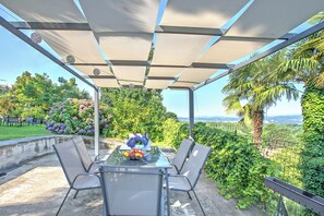 An outdoor patio with a glass table, metal chairs, and a view of the landscape. - Villa La Rocca (Taino)