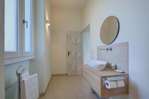 A modern bathroom with a white sink, a large mirror, and a towel rack. - Villa La Rocca (Taino)