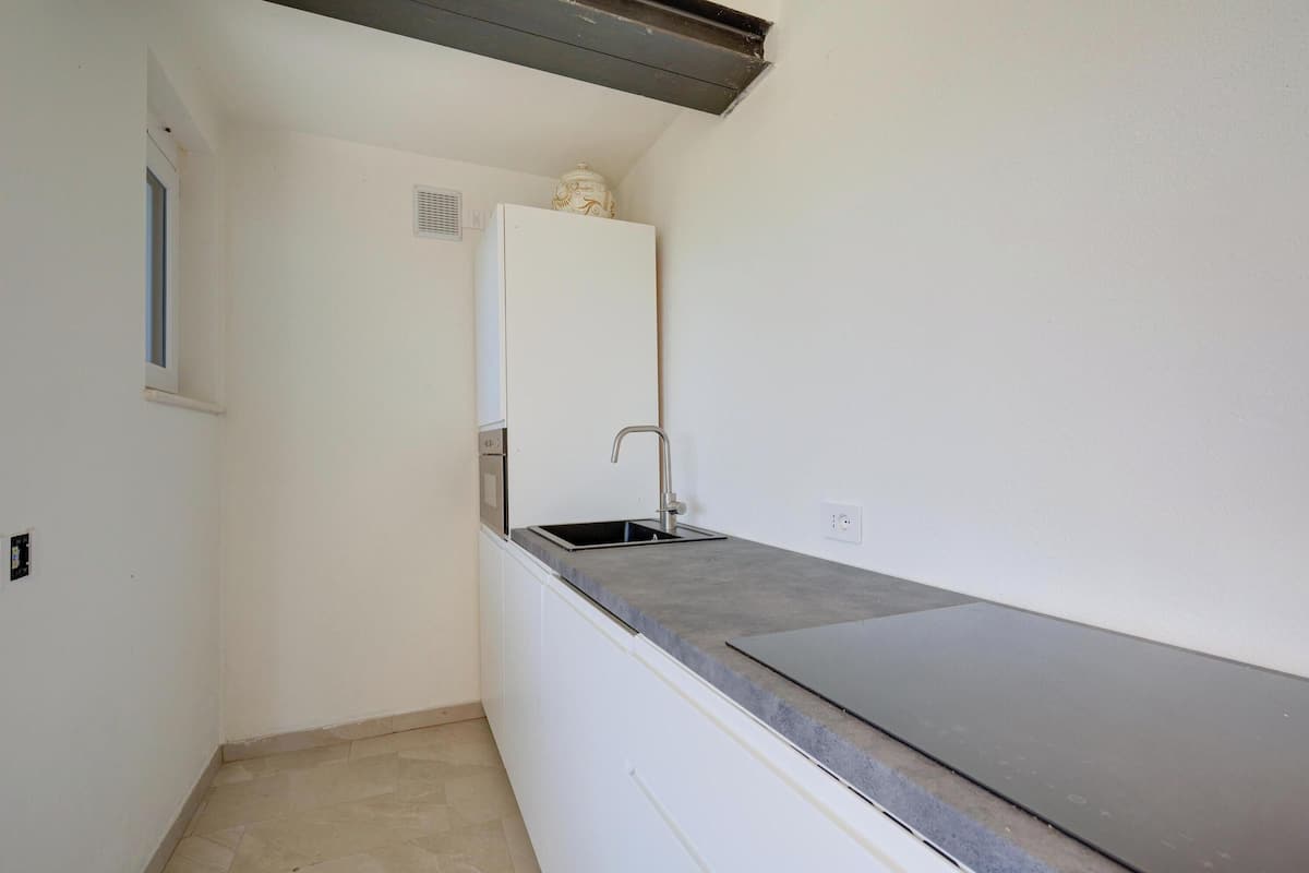 A small kitchen with a white refrigerator, a sink, and a countertop.